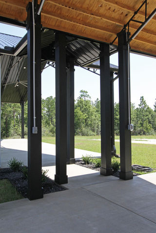 a row of black pillars under a covered area with trees in the background