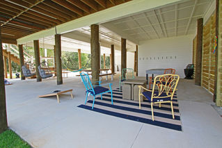 a patio area with chairs tables and a striped rug