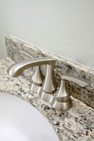 a bathroom sink with a stainless steel faucet and granite counter top