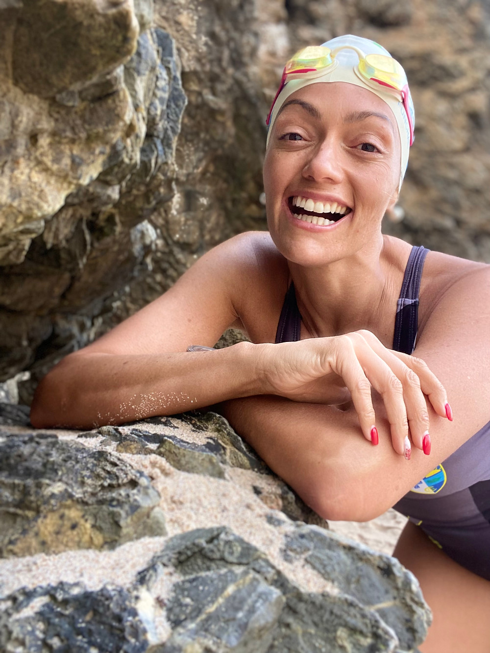 This photo shows Mayra Santos smiling while resting at rocks by the beach.