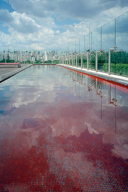 Ein Pool auf dem Dach eines Hotels in Sap Paulo. Im Hintergrund sieht man die Skyline der Metropole. Die Kacheln des Pools sind rostrot.