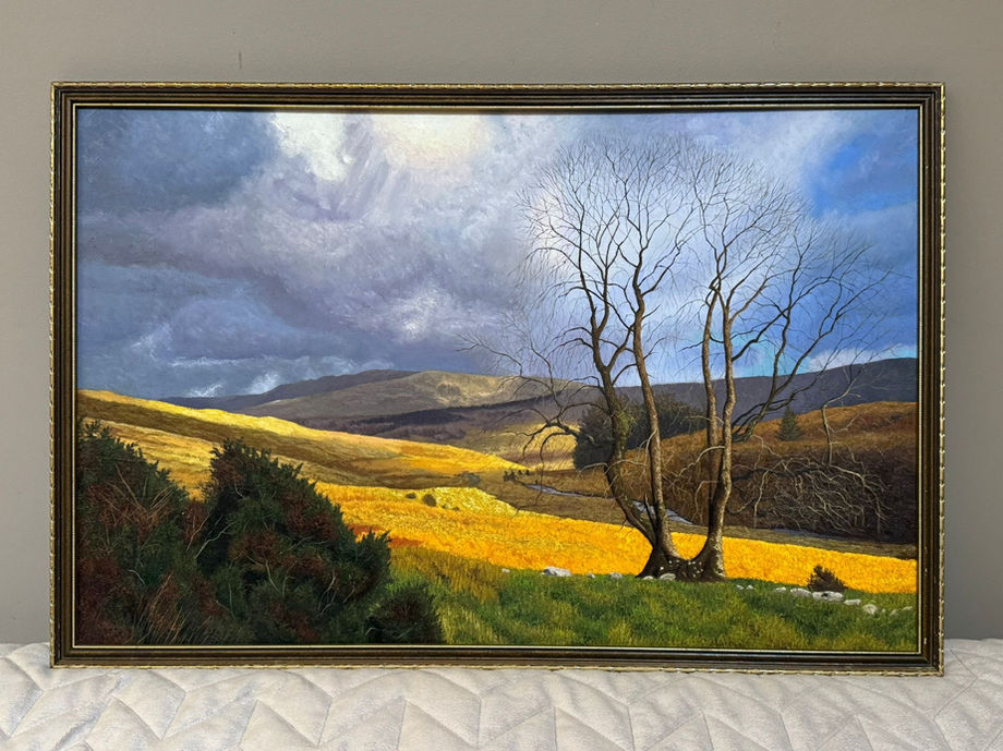 Original oil painting of Wales. It features a twin trunk bare tree on the right of the foreground, sitting on a plain of green grass. The midground is a field of golden fields and receding mountains going towards the background. The sky holds wavy blue, grey and gold clouds.