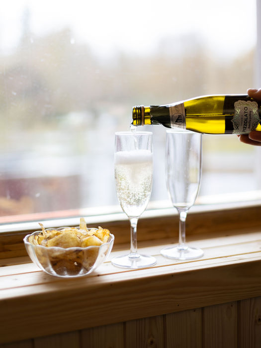 Påfyllning av bubbel i två glas och en skål med chips i Storsätras relaxavdelning