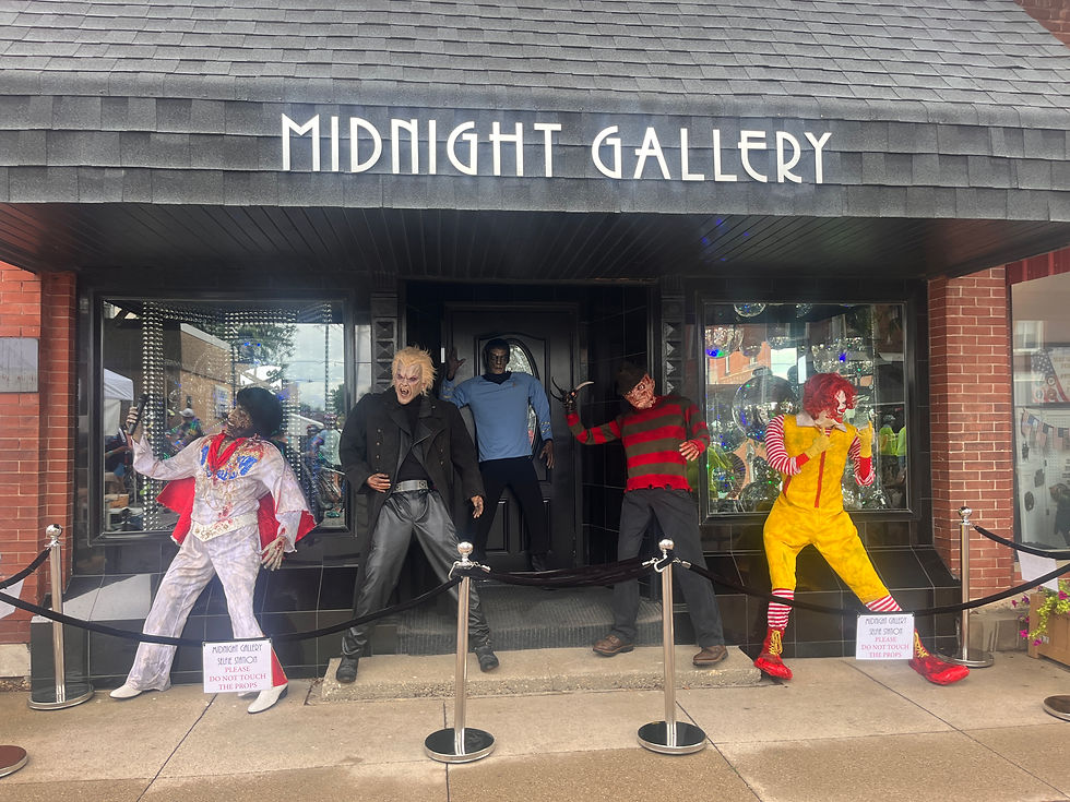 Five horror-themed mannequins in front of Midnight Gallery; vibrant costumes; black awning; signs ask not to touch props.