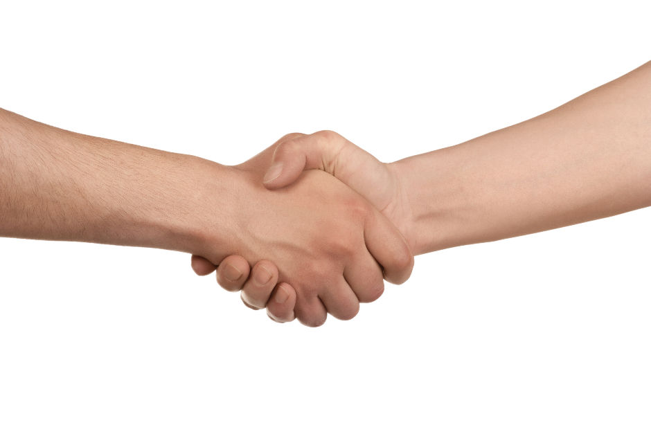 Two hands are shaking against a plain white background, symbolizing agreement or partnership. The skin tones differ slightly.