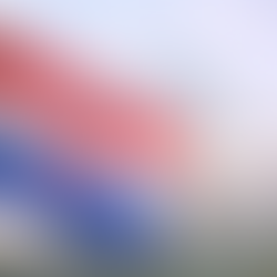 Croatian flag with red, white and blue stripes and central coat of arms, captured in close-up with a blurred urban background.