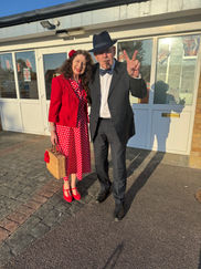 A man in a tuxedo and a woman in a dark green velvet dress posing in front of a holiday backdrop