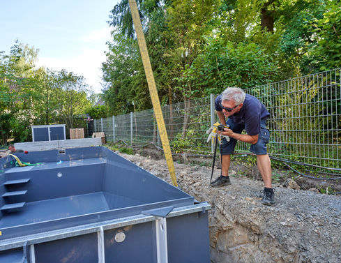 Dirk Lodders gibt Anweisung zur präzisen Platzierung eines Veltmann Schwimmbades in einem Garten auf einer Baustelle