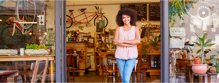 A photo of a smiling woman with kinky hair standing in front of a store with bikes and furniture