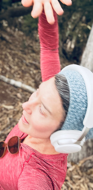 Romy Limenes wearing headphones outdoors with her arm raised