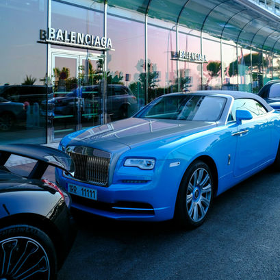 A Rolls-Royce car in front of a Balenciaga store.