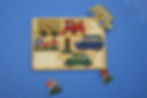 A half finished puzzle with varying colourful vehicles on a padded blue floor.