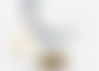 Decorative crescent moon with blue patterns on wooden stand, next to a lit white candle on a white surface. Calm and serene setting.