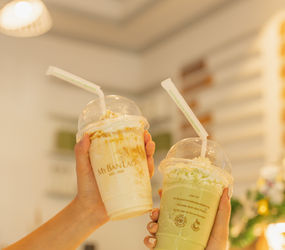 Two hands toasting with iced coffee drinks in eco-friendly takeaway cups from Cafe 1960 at MyBanLao
