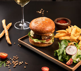 The signature water buffalo burger from Bistro 1960, served with French fries, a side salad, and a glass of white wine