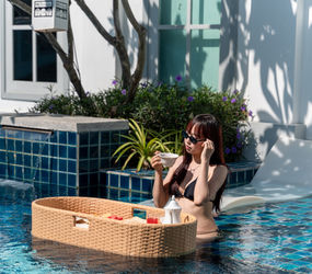 A guest sipping tea while enjoying the floating tray breakfast service in the swimming pool at a MyBanLao pool access room