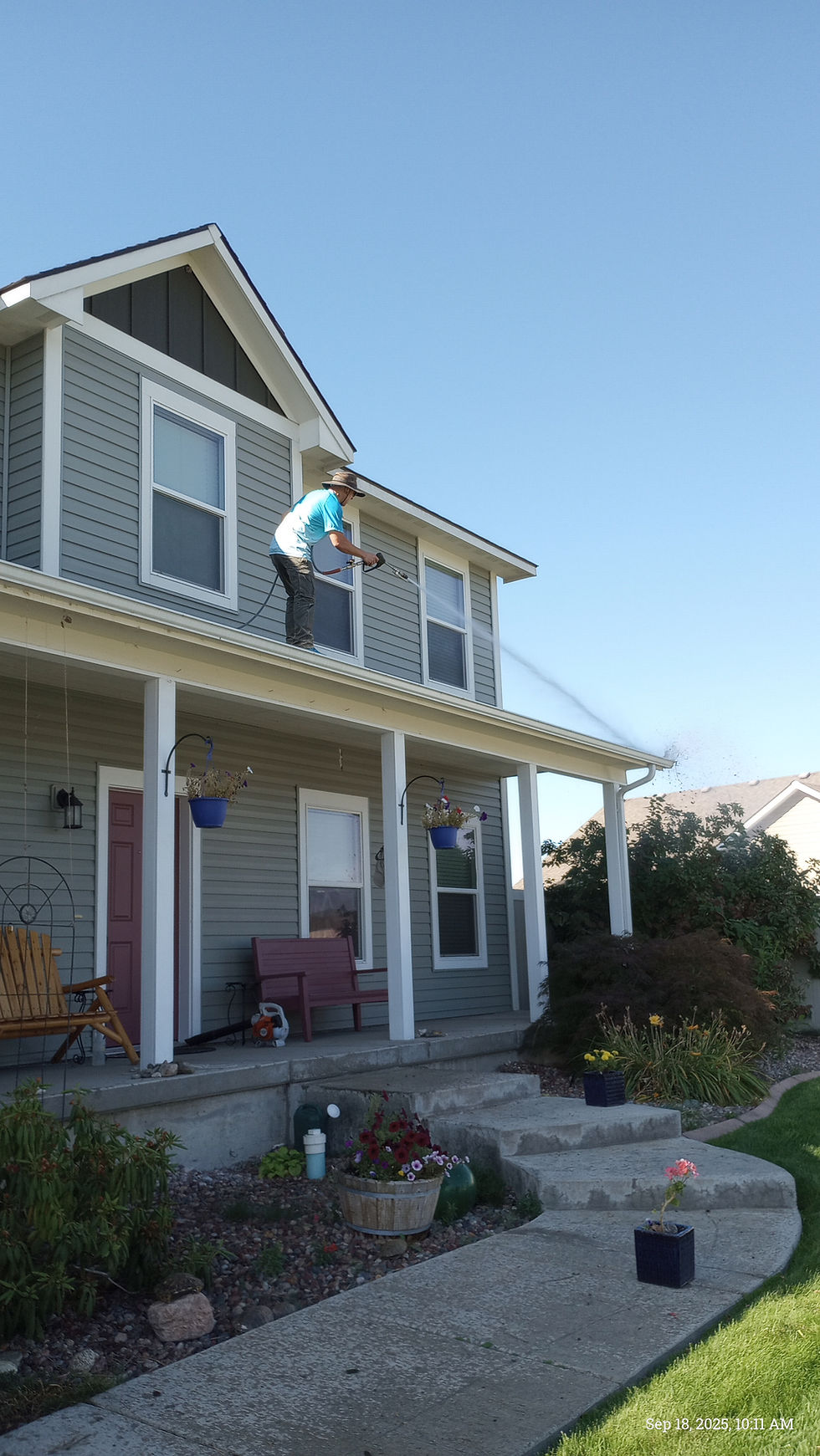 Worker performing Central Minnesota Gutter Cleaning on a house.