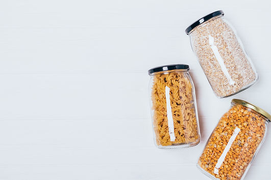 Flat lay glass jars with dry peas, oat flakes and pasta on white wooden table with copy sp