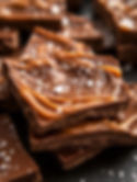 A close-up shot of Caramel Chocolate Bark, rich chocolate, gooey caramel swirls, flaky sea salt, professional food photography, dark background, elegant styling
