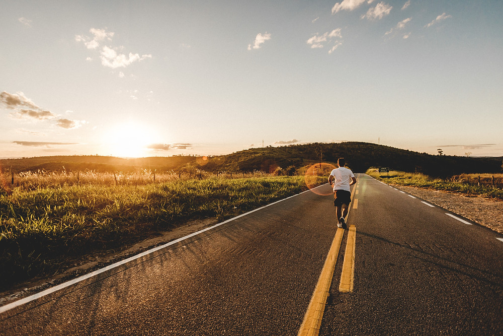 Man running on open road during the sunset