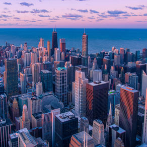 Aerial view of a vibrant city skyline at dusk, with tall buildings under a pink and blue sky near a lake. Chase building visible.