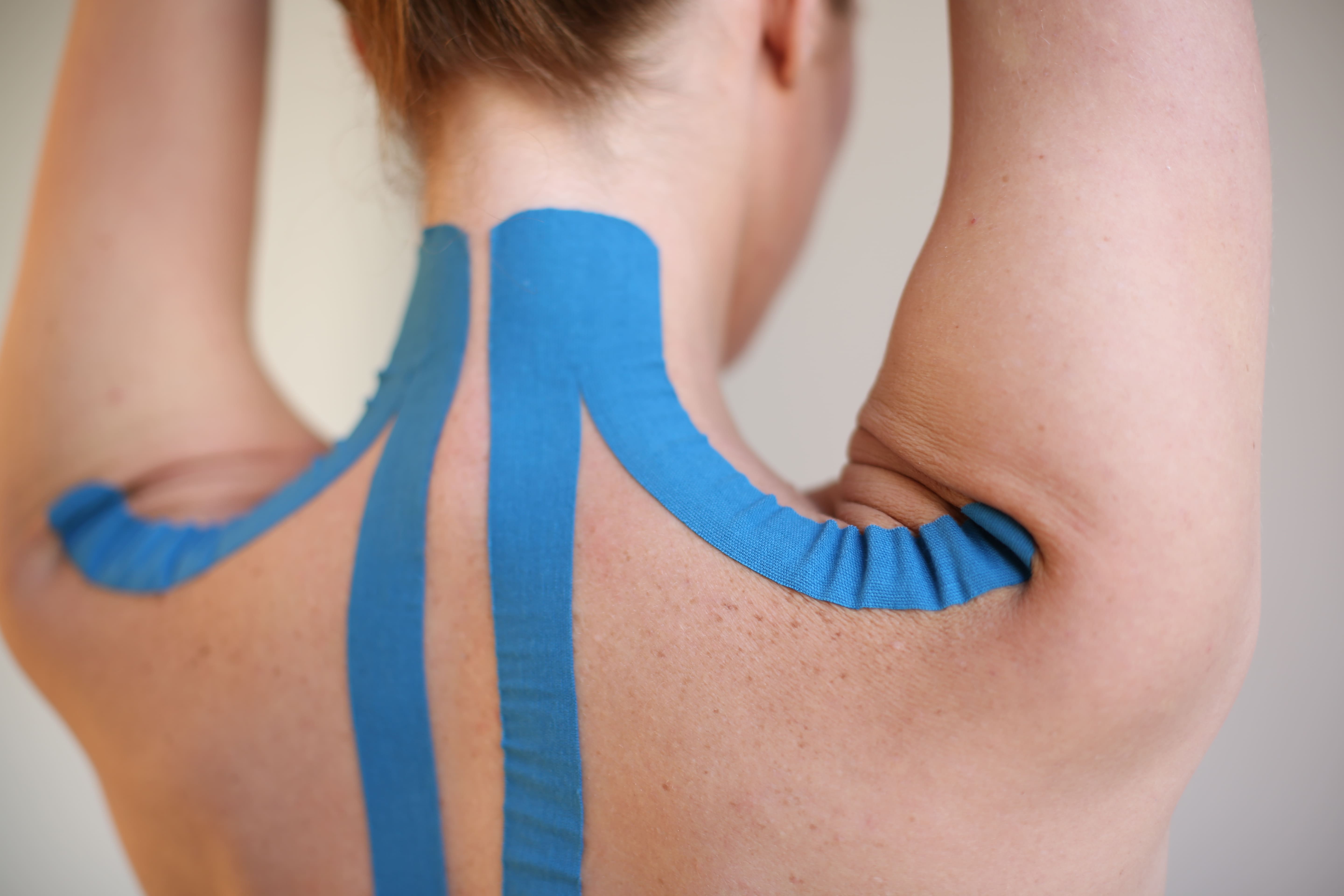 a young woman with athletic sports tape on the back and neck