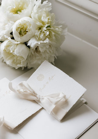 Papeterie et accessoires de mariage accompagnés d'un bouquet blanc