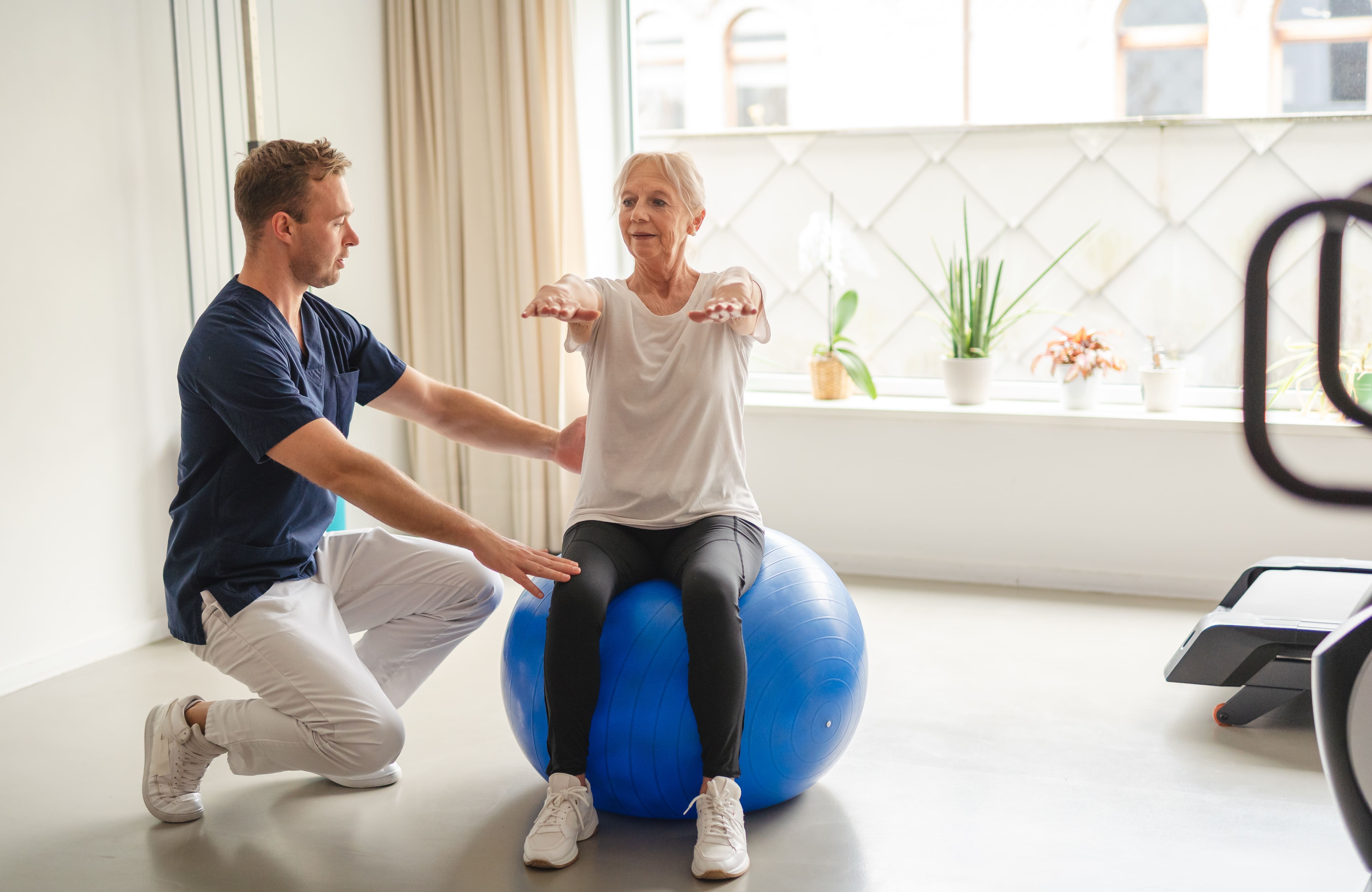 Un jeune physiothérapeute guide une femme âgée à travers des exercices de réadaptation, lui donnant les moyens d'avancer sur la voie du bien-être