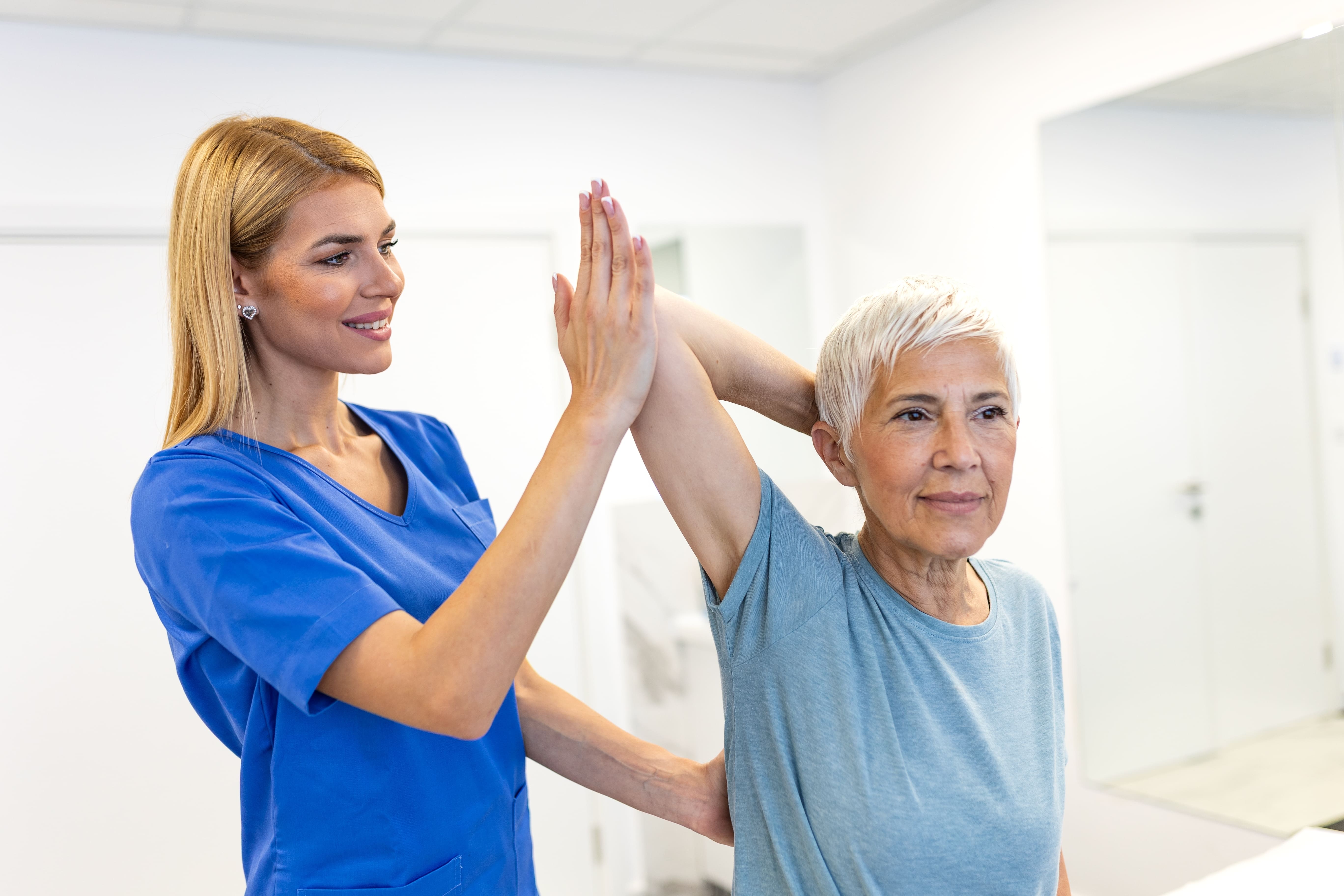 Séance de physiothérapie pour les aînés. Femme âgée ayant un problème de bras, concept Soins de santé et médecine. Professionnel physiothérapeute en uniforme bleu aidant le patient avec l'exercice d'étirement d'épaule.