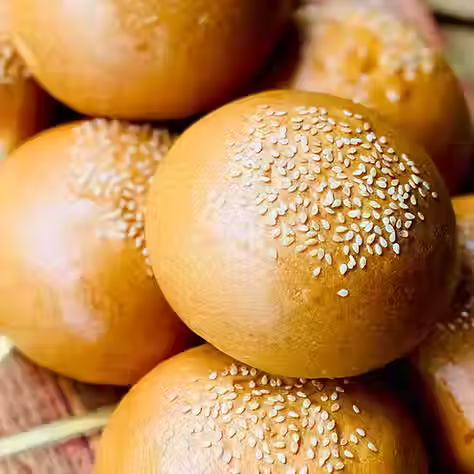Burger buns topped with sesame seeds on a chopping board