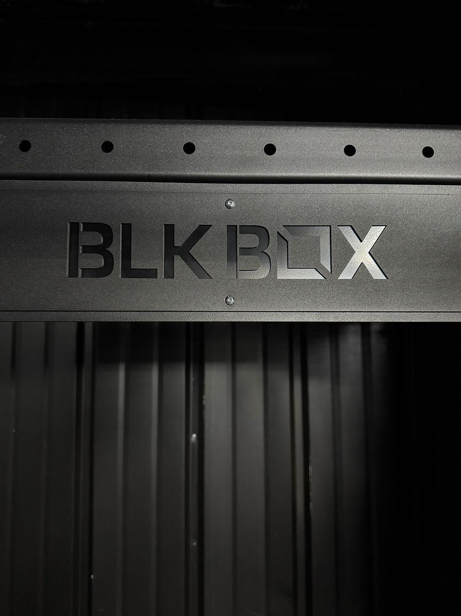 Black metal with the cutout text "BLK BOX," featuring a modern, minimalist design against a dark, industrial backdrop