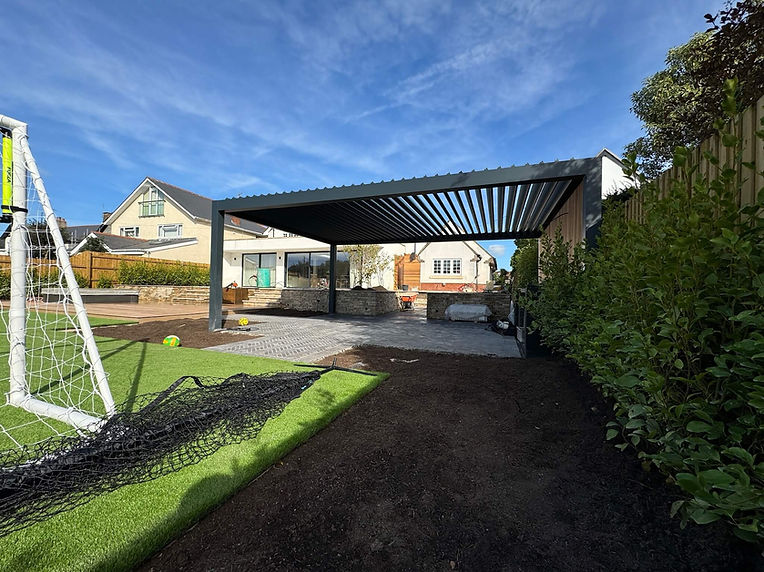 Anthracite grey bioclimatic pergola with louvered roof, timber cladding and kitchen unit, designed as outdoor dining area and kitchen.