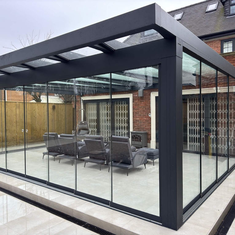 Anthracite grey glass room with a glass roof, furnished with grey sun loungers.