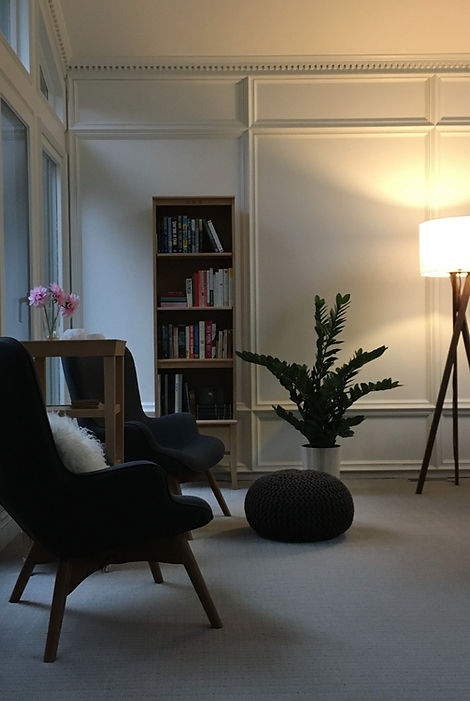 01_living05_edited.jpg Cream coloured walls and geometric patterned carpeting, high back modern chairs. Light wood accents