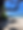 serene beach scene with greenery, black rocks, and blue sky and ocean
