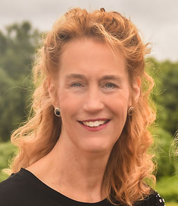 Portrait of the founder, Cynthia Love-Williams, smiling with curly hair, black earrings, and read lipstick.