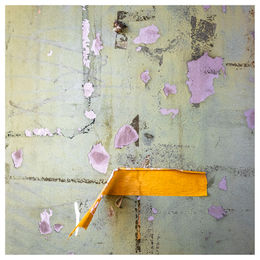 orange adhesive tape, half of which is stuck to a wall with peeling paint