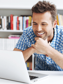 Adult learner smiling while taking a private conversational online French lesson on a laptop.