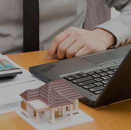 desk computer man typing on a calculator and house statue