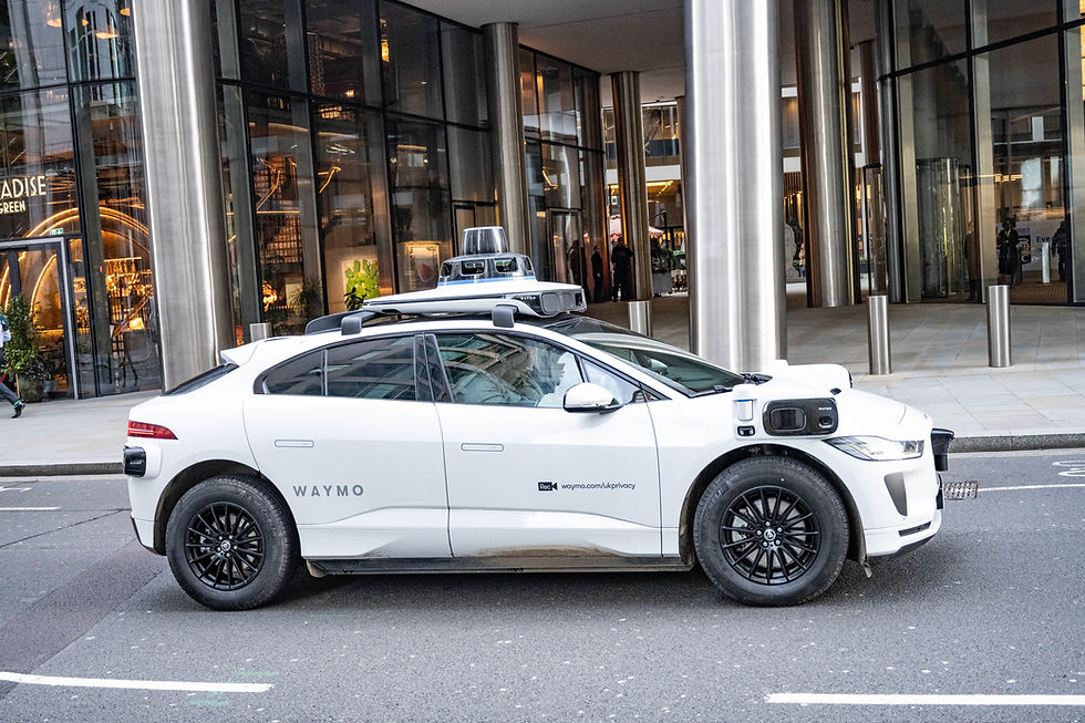 A white driverless car on a London street in the daytime with 3D cameras on the roof and bonnet.