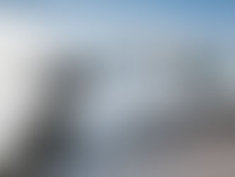 White electric van charging in the foreground, with a line of similar vans parked in the background under a clear blue sky.