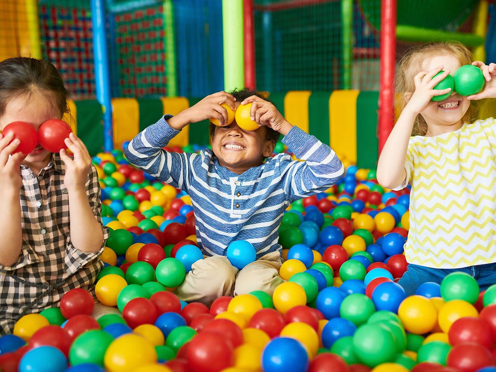 Children laughing and playing in a colorful indoor ball pit during a birthday party in Greenville.