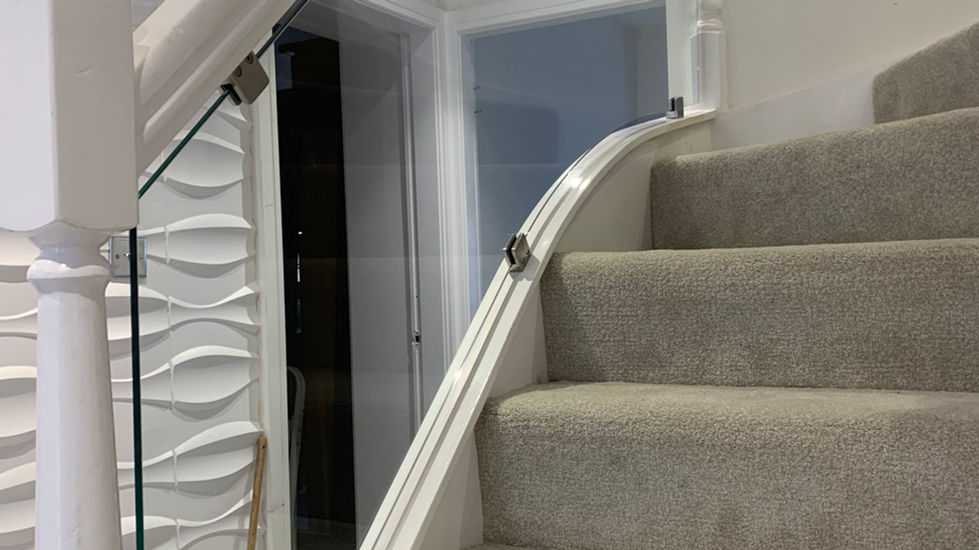 Modern white staircase featuring clamped glass panels