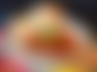 Chili topped with a sprig of parsley on a white bowl, laid on a cloth placemat surrounded by metal spoons and bread rolls.