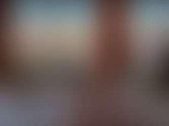 Feet visible in a bubble bath with a book and wine glass on a wooden tray. A sunset view through a window creates a serene atmosphere.