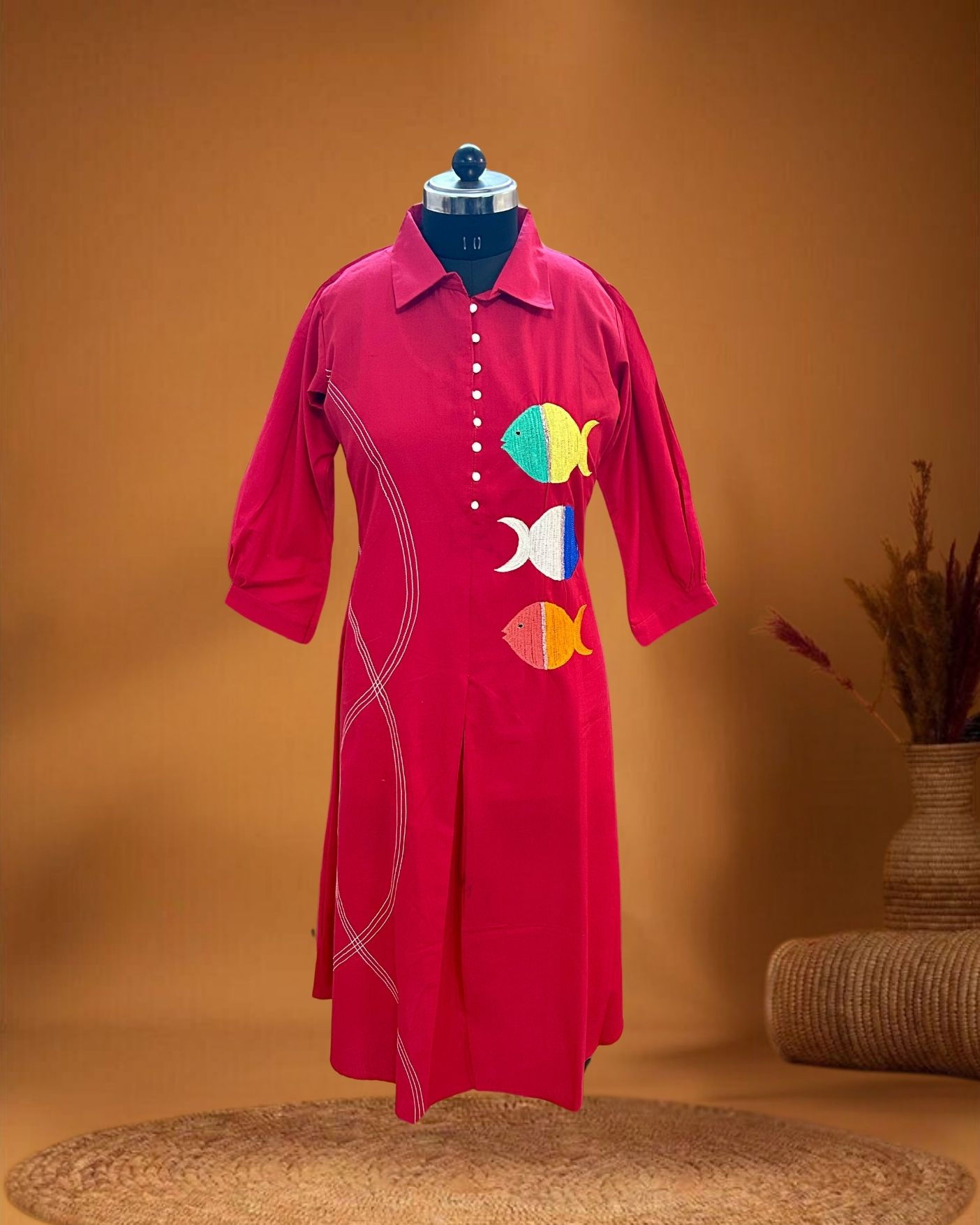 Front view of red dress with three colorful embroidered fish motifs and daana embellishment – Sutralasya