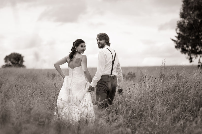 Brautpaar beim Paarshooting mit dem Hochzeitsfotografen geht über eine Wiese mit hohem Gras

