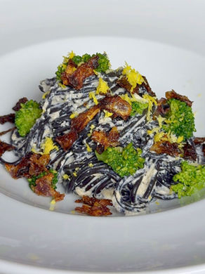 Siyah spagetti, limon ve karamelize soğan bazında yumuşak ama dikkat çekici bir tabakta buluşuyor. Üzerinde minik brokoli çiçekleri, altta parmesanlı ricotta sosu… Tabağın hem rengi hem tadı dengede. 🍋🖤🥦
