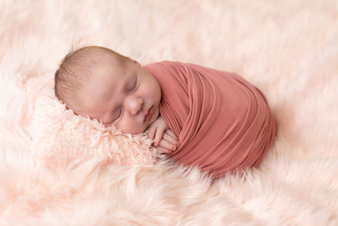 Newborn photographer in Gilmer TX capturing baby girl wrapped in pink during fine art studio session.