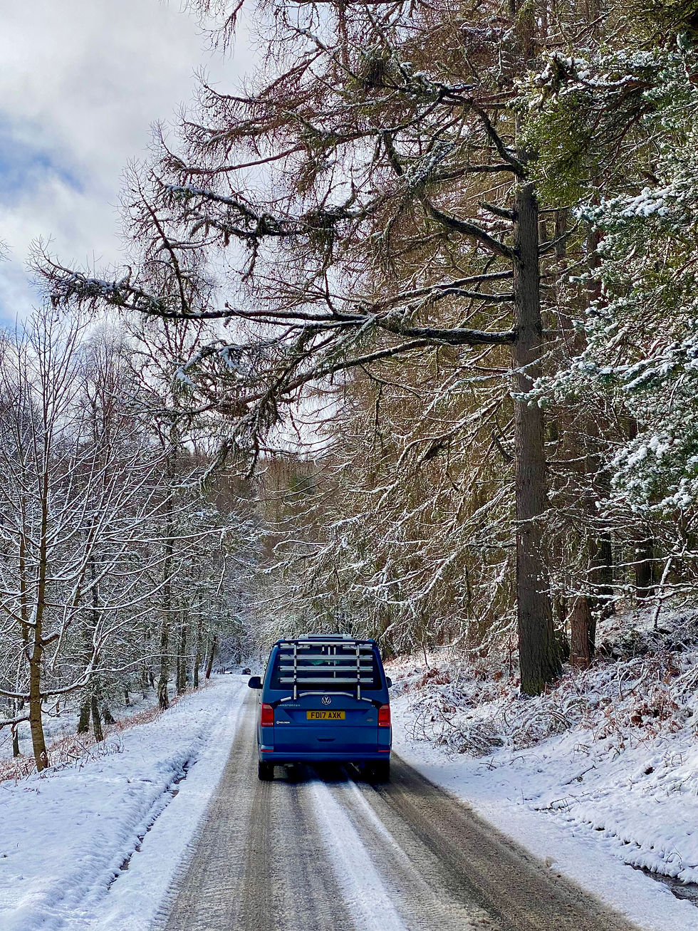 VW campervan driving through snowy forest